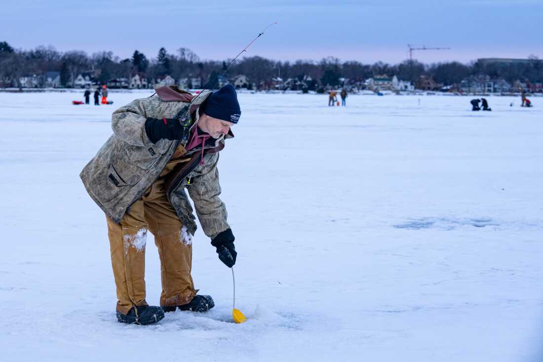 Tony Pavlak récupère la neige fondante de la surface de l'eau d'un trou foré dans la baie de Monona alors qu'il pêchait sur la glace le samedi 7 février 2026 à Madison, Wisconsin. Photo de Kayla Wolf