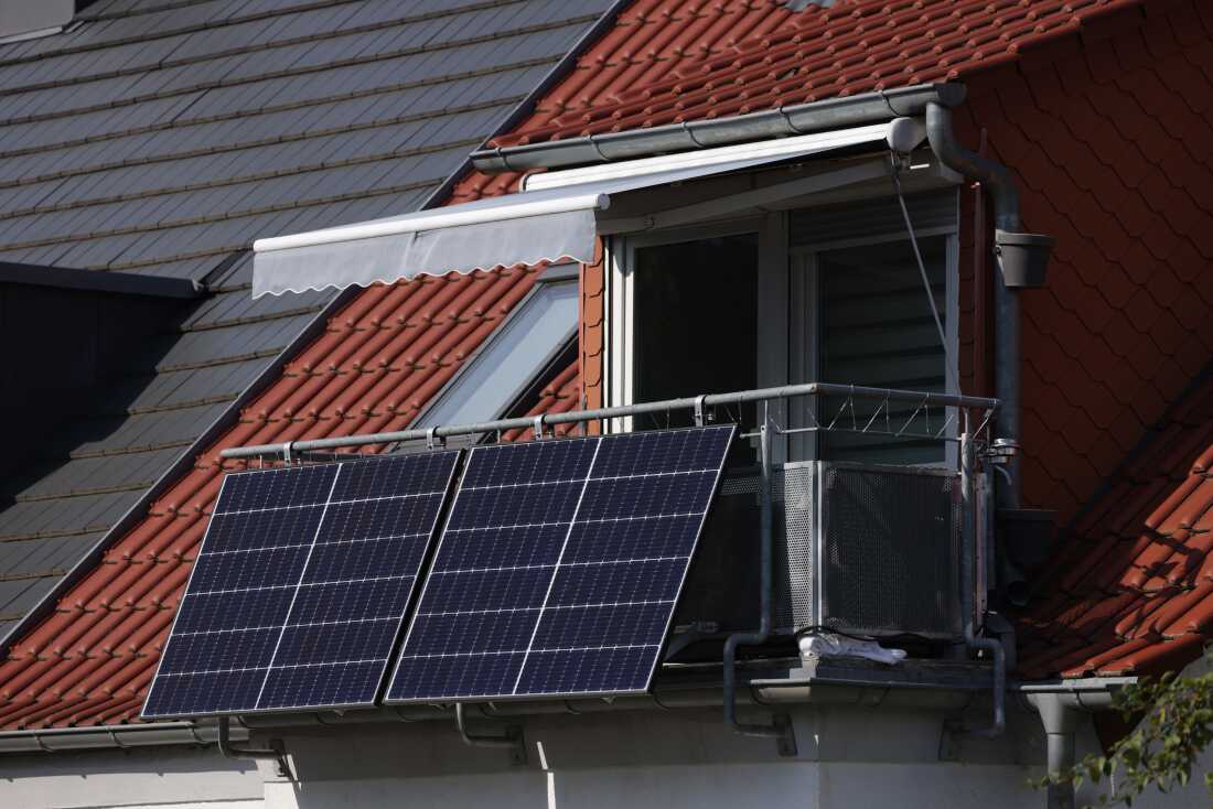 Des panneaux solaires rectangulaires noirs sont suspendus à l'extérieur du balcon d'un appartement résidentiel à Erfurt, en Allemagne.