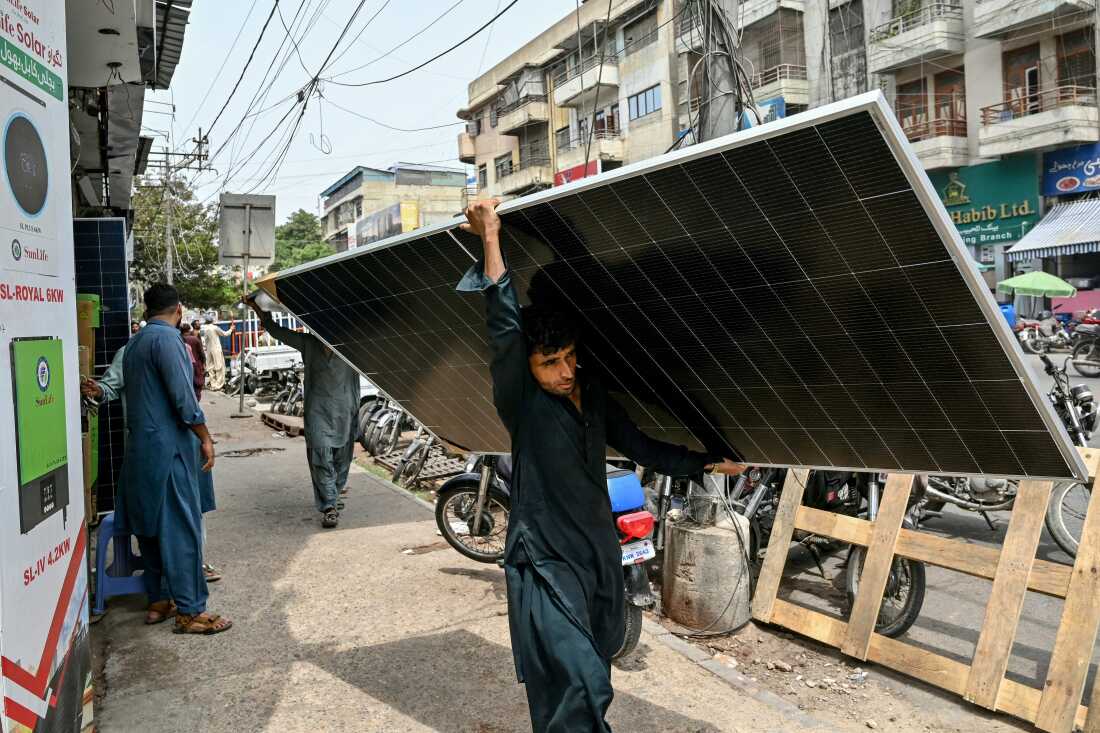 Un ouvrier traverse Karachi avec un panneau solaire