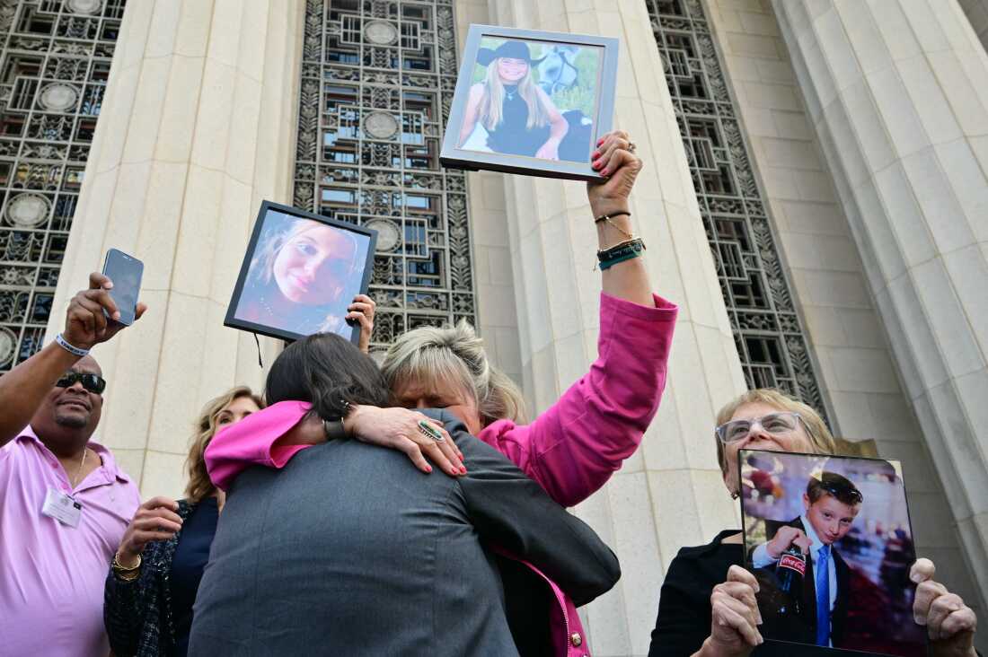 Les proches des victimes brandissent des portraits de leurs proches, et deux d'entre eux s'embrassent à la sortie du palais de justice.