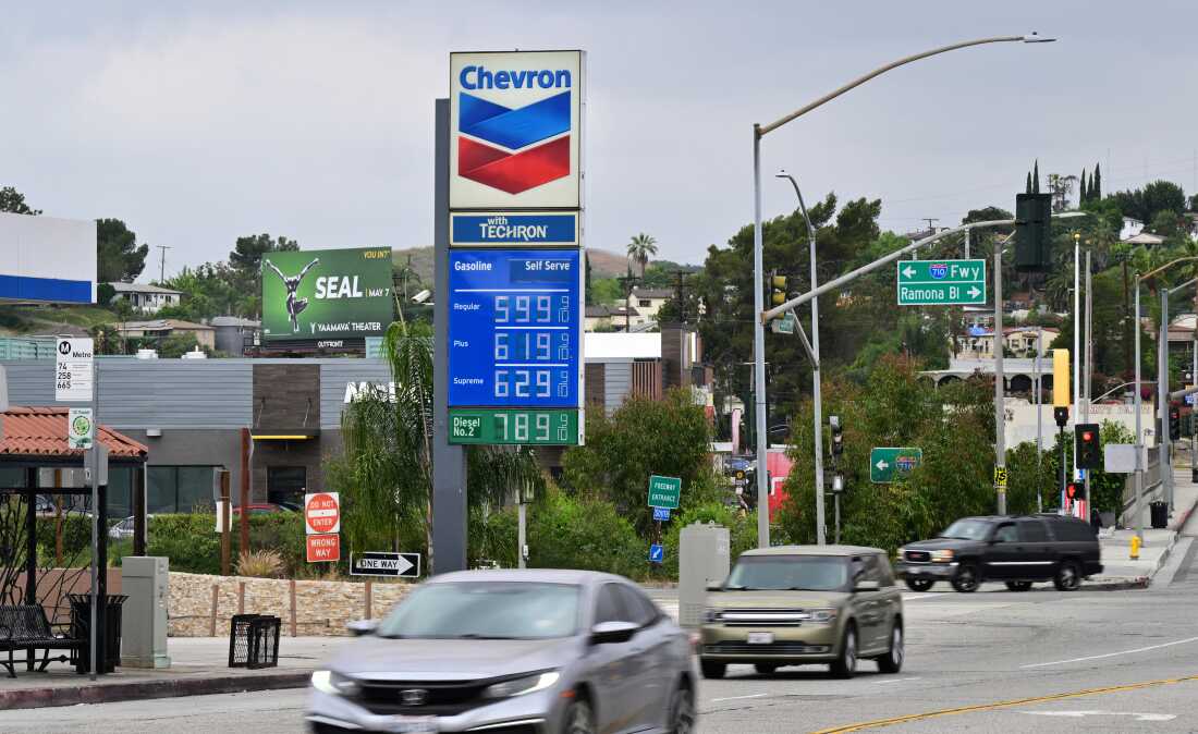 Les prix de l'essence sont affichés sur un grand panneau dans une station-service Chevron à Los Angeles le 31 mars. Des voitures passent dans la rue.