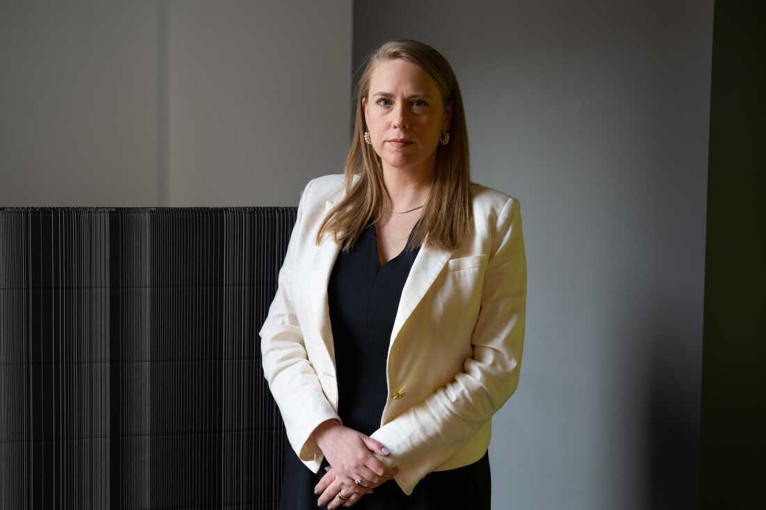 Andrea Lucas se tient près d’un mur rayé noir et gris.
