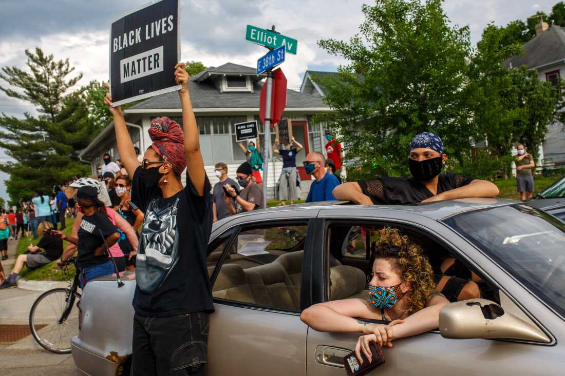 Les gens brandissent des pancartes et protestent après le meurtre de George Floyd par un policier de Minneapolis en mai 2020.