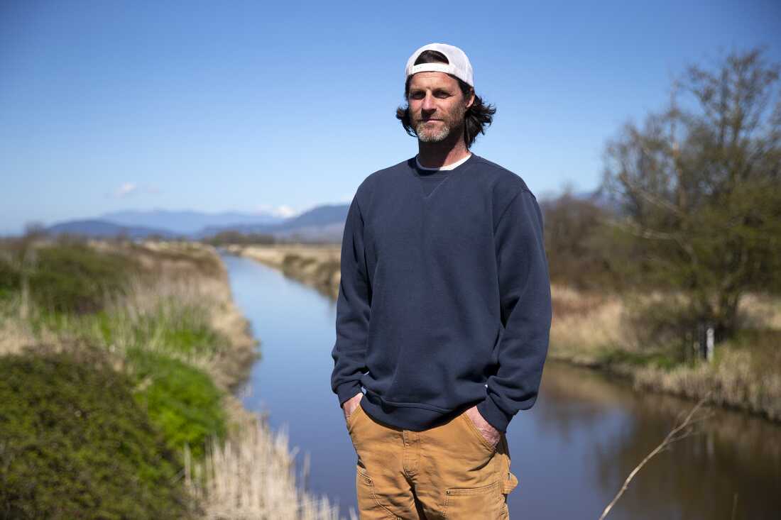 Tyler Breum, agriculteur de cinquième génération, se tient le long de la digue de Tom Moore Slough, près de Big Ditch, à proximité des terres agricoles de sa famille, le 8 avril 2026, près de Stanwood, Washington.