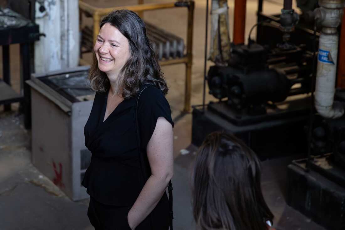 Elizabeth Babcock se tient dans l’ancienne chaufferie Cherokee, à proximité d’équipements d’aspect industriel.