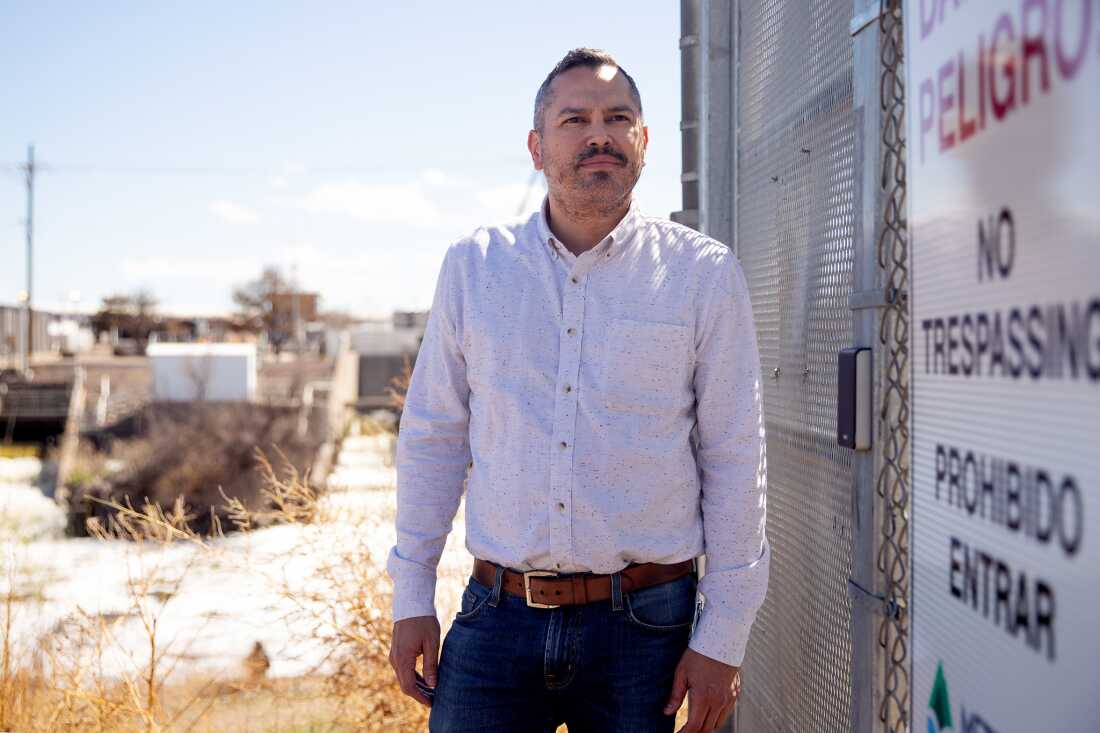 Daniel Freedman se tient à côté d'une clôture métallique dans l'installation de traitement de Metro Water Recovery, le long de la rivière South Platte, à Denver. L'installation est en arrière-plan.