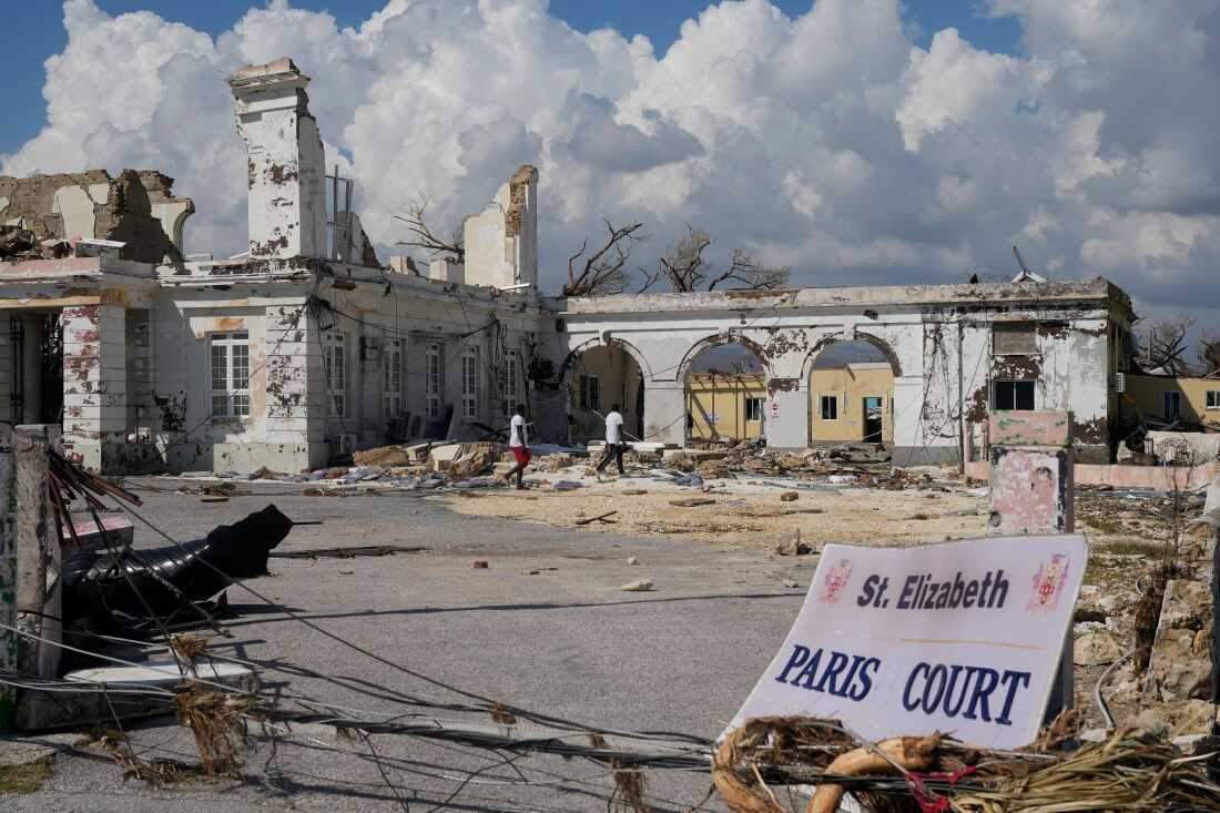 Des gens passent devant les dégâts causés par l'ouragan Melissa à Black River, en Jamaïque, le jeudi 30 octobre 2025. 