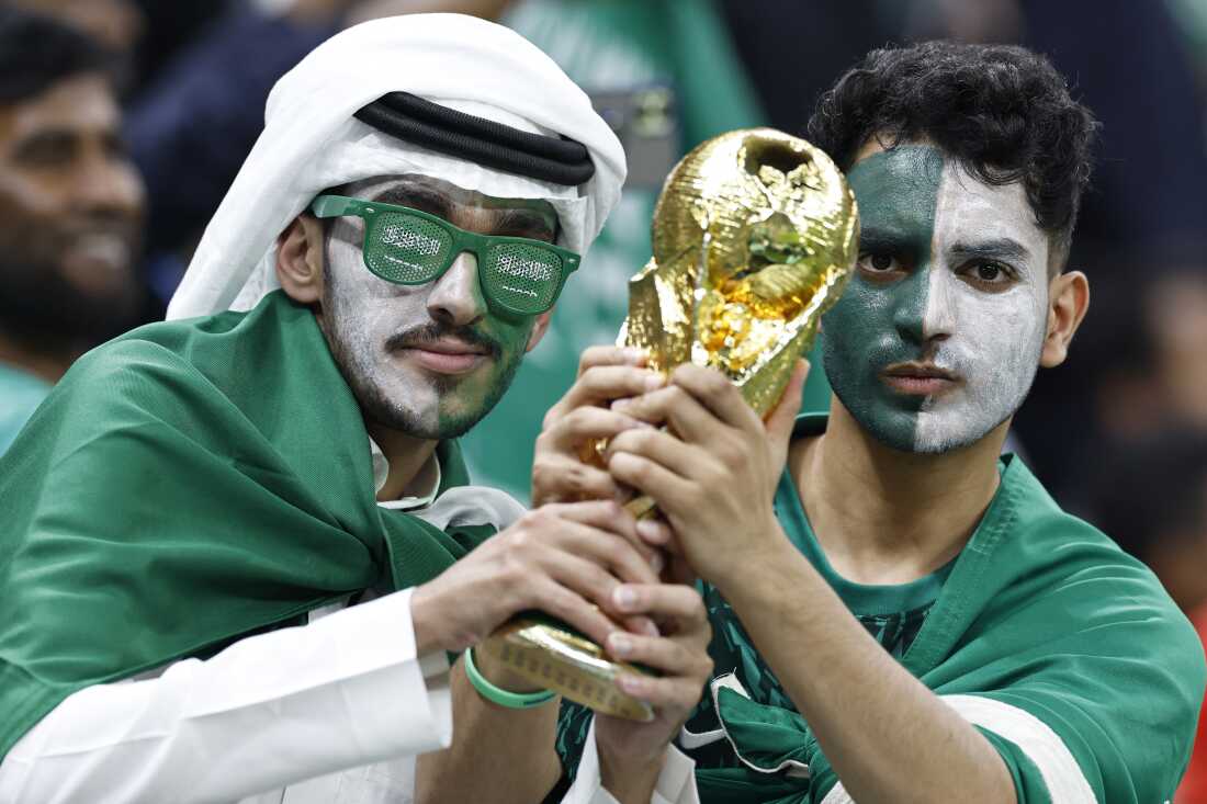 Les supporters saoudiens tiennent une réplique du trophée de la Coupe du monde de la FIFA avant un match entre l'Arabie saoudite et le Mexique au stade Lusail au Qatar lors de la Coupe du monde 2022.