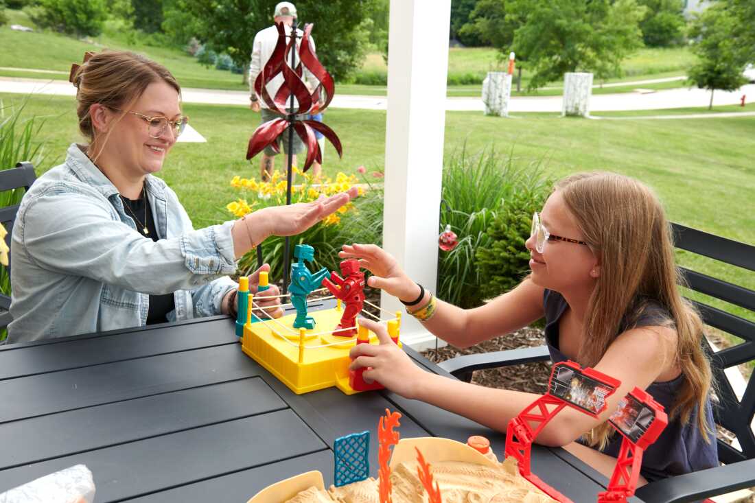 Amber et Piper, 12 ans, jouent ensemble avec des robots en plastique sur une terrasse.
