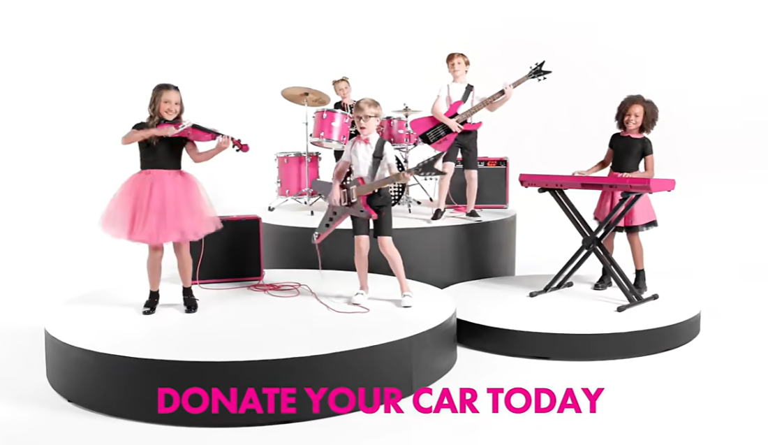 Une image tirée d'une publicité télévisée de Kars4Kids, montrant des enfants jouant d'instruments roses et les mots "faites don de votre voiture aujourd'hui." 