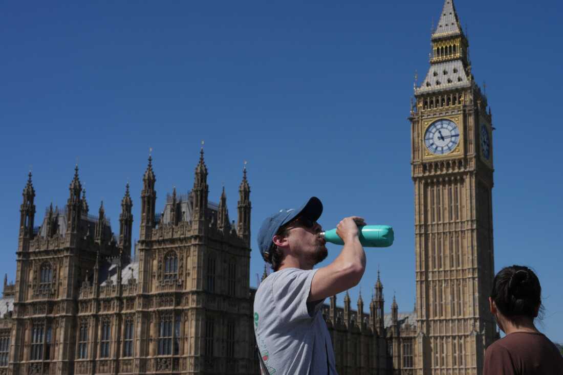 Un homme boit mardi devant le palais de Westminster à Londres.