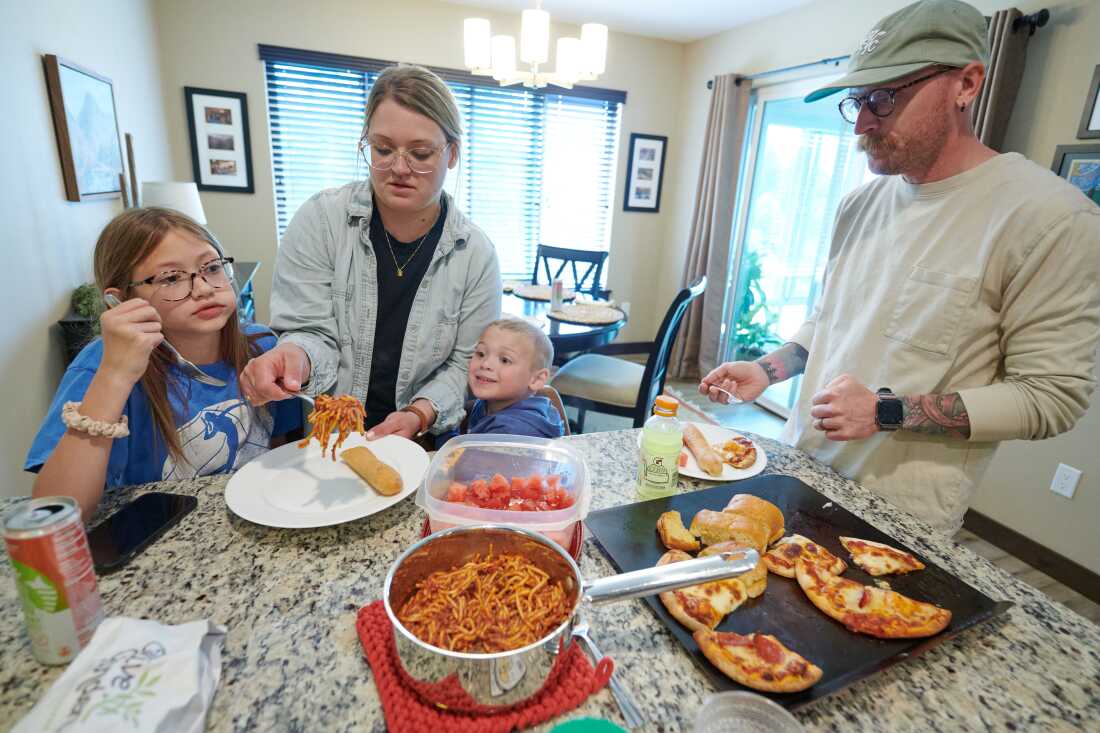 Amber et Neil Petersen servent des pâtes, des pizzas et des fruits à leurs enfants, Eden, 11 ans, et Jack, 4 ans, à Iowa City, Iowa. Ils se tiennent autour d’un comptoir encombré.