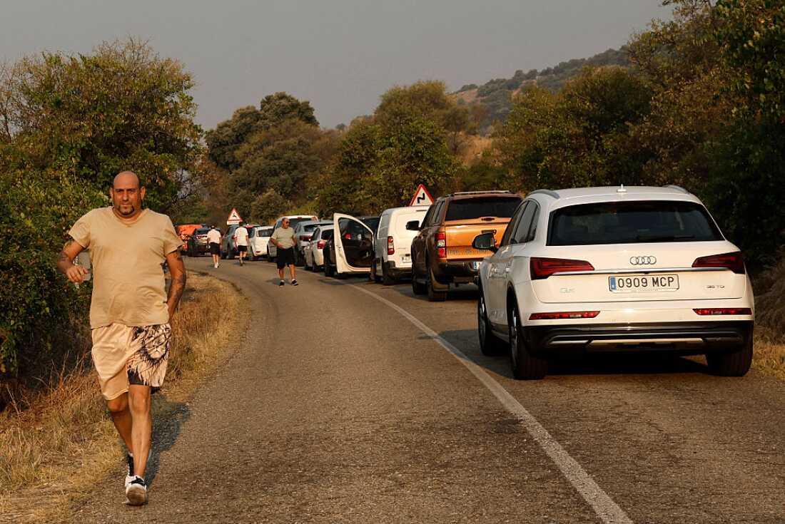 Les conducteurs sont arrêtés dans une longue file de circulation. Certaines personnes ont abandonné leur véhicule et courent sur le bord de la route.