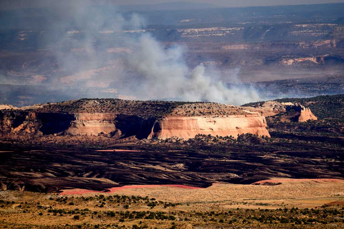 La fumée de l'incendie de Snyder apparaît au-dessus d'une haute formation rocheuse près de Thompson Springs, dans l'Utah, le 28 juin.