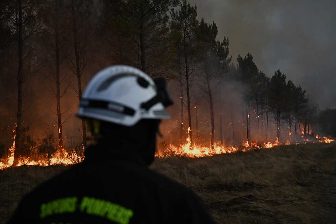 Un pompier marche devant des arbres en feu alors qu'un incendie de forêt fait rage près de Marcheprime, à l'extérieur de Bordeaux, France, le 26 juillet 2026.