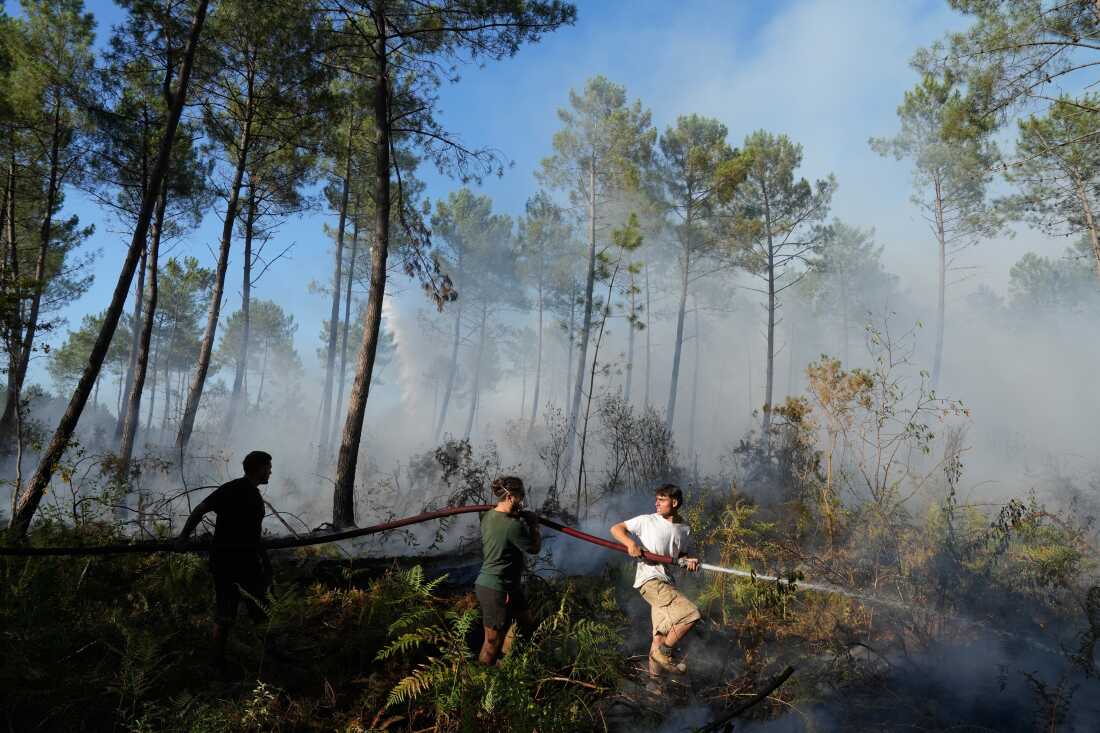 Un groupe tient une lance à incendie et tente d'éteindre un incendie près de Lacanau, alors que les incendies de forêt font rage à l'extérieur de Bordeaux, en France, le lundi 27 juillet 2026.