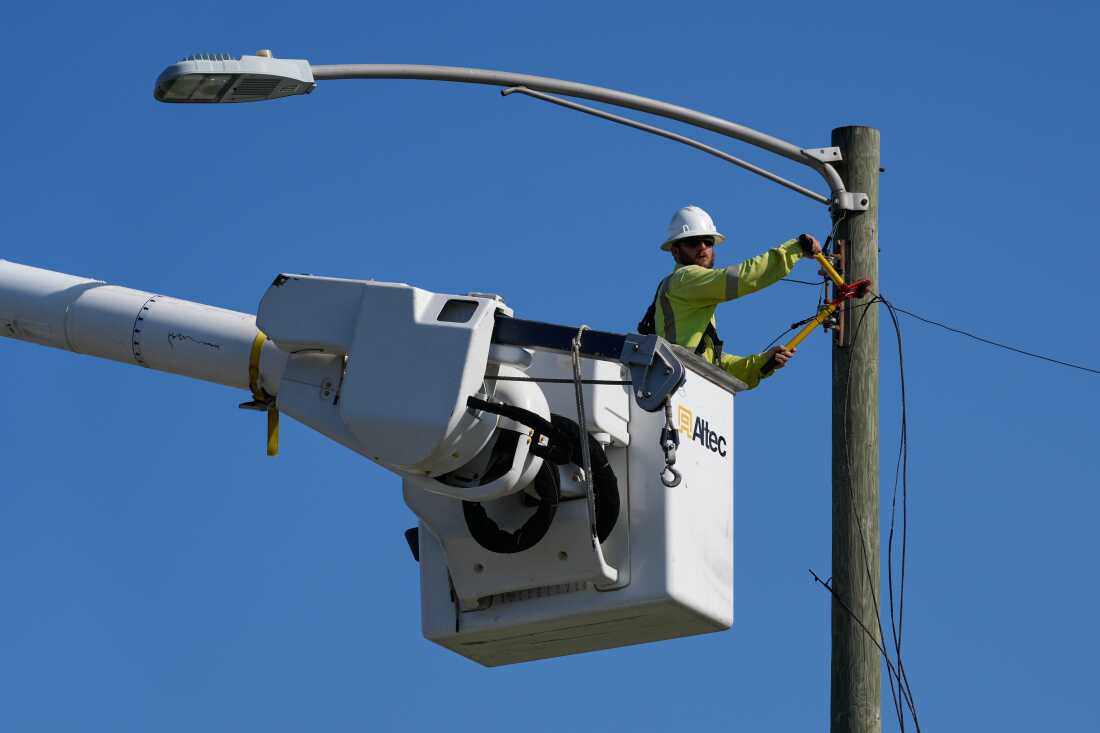 Un électricien répare les lignes électriques le long d'une rue à Gary, Indiana, le jeudi 20 août 2026, plus d'une semaine après le passage d'une tempête mortelle dans la région.