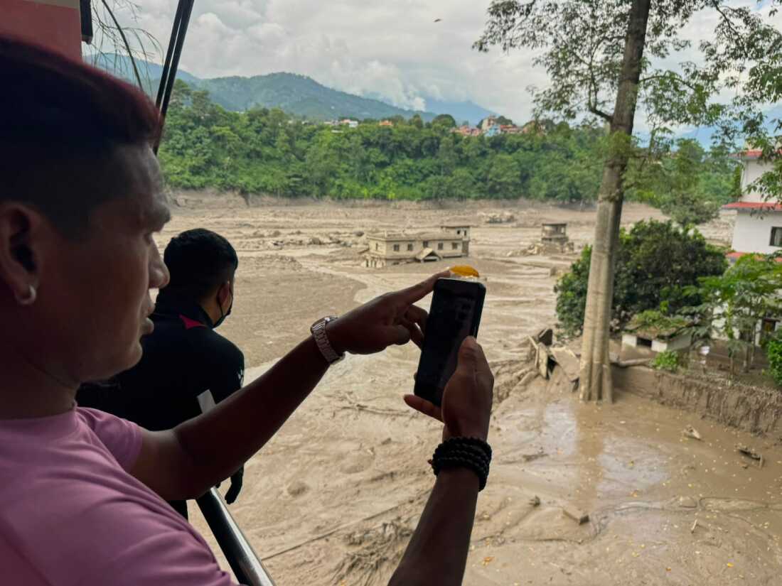 Des gens prennent des photos et des vidéos des berges gonflées et obstruées par les débris de la rivière Trishuli après des crues soudaines dans le district de Nuwakot au Népal, le mercredi 26 août 2026.