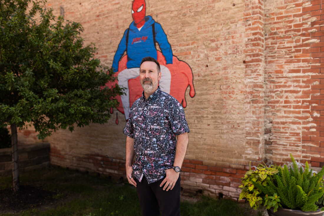 Bowker se tient à l'extérieur du magasin devant une fresque murale de Spiderman.