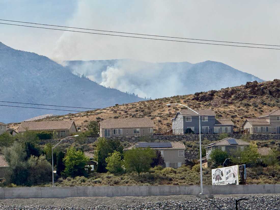 De la fumée s'élève au loin alors qu'un incendie de forêt brûle à Reno, Nevada, le dimanche 23 août 2026. 