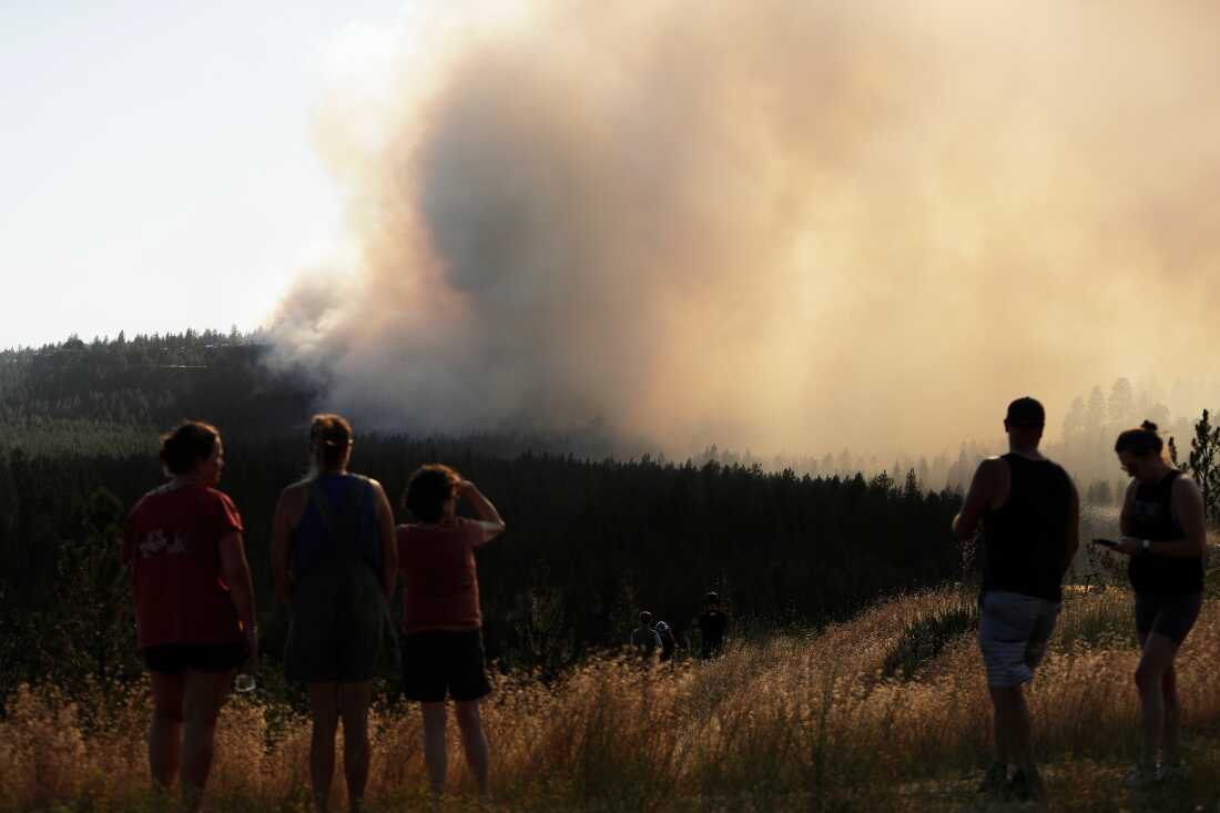 Des gens regardent l'incendie d'Old Trails depuis W. Northwest Blvd., le samedi 1er août 2026, à Spokane, Washington.