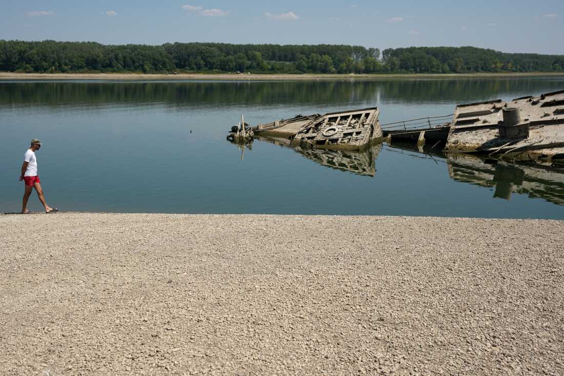 Un homme marche sur le banc de sable près de l'épave d'un navire de guerre allemand de la Seconde Guerre mondiale, émergé à cause de la sécheresse, devant Djerdap II, un grand barrage sur le Danube, entre la Roumanie et la Serbie, près de Prahovo, en Serbie, le mardi 4 août 2026.