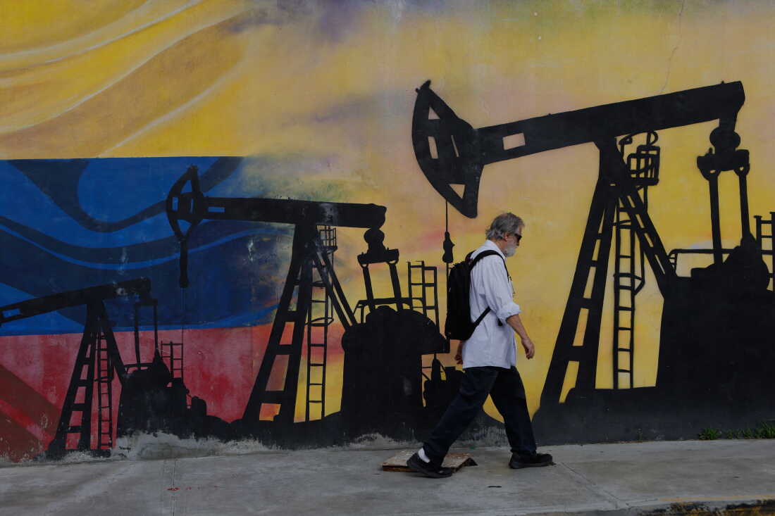 Un piéton passe devant une fresque représentant des puits de pétrole à Caracas, au Venezuela, le samedi 29 août 2026, un jour après que le président Donald Trump a annoncé un accord donnant aux États-Unis une participation dans les réserves de pétrole du Venezuela. (Photo AP/Pedro Mattey)