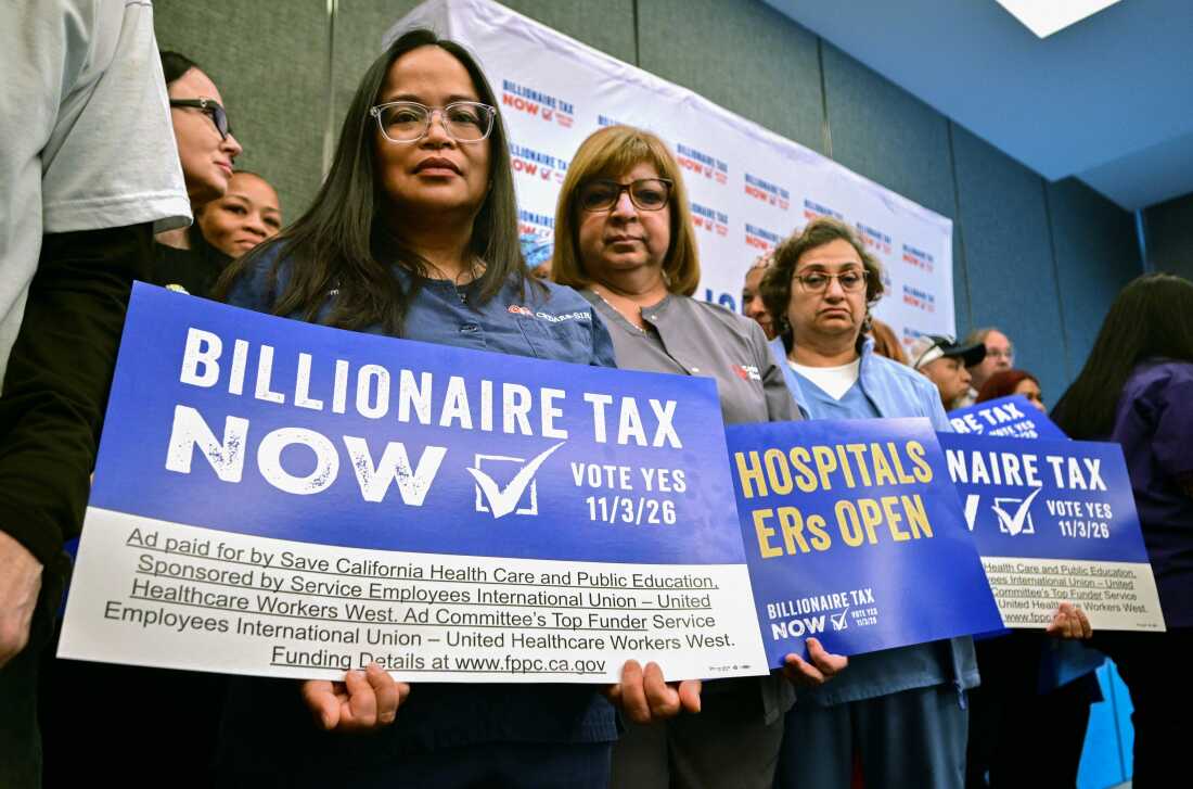 Des professionnels de la santé et d'autres partisans de la coalition Billionaire Tax Now tiennent des pancartes lors d'une conférence de presse à Los Angeles le 27 avril 2026. L'initiative prélèverait une taxe unique de 5 % sur les milliardaires californiens.