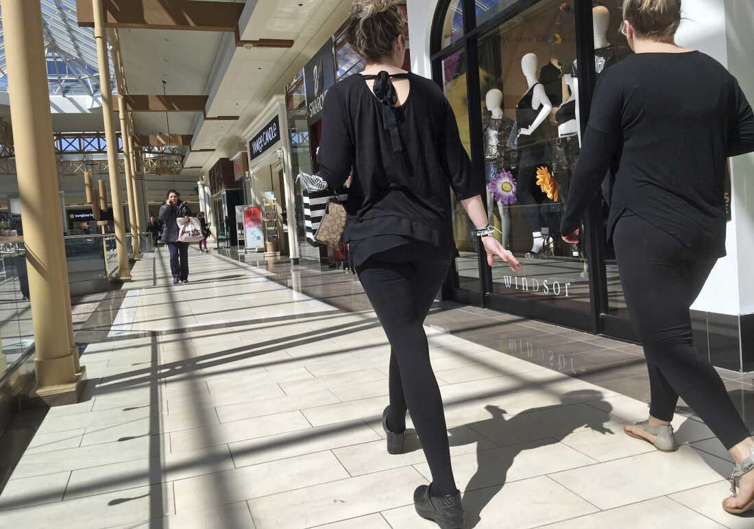 Les gens marchent dans un centre commercial, devant une rangée de magasins.