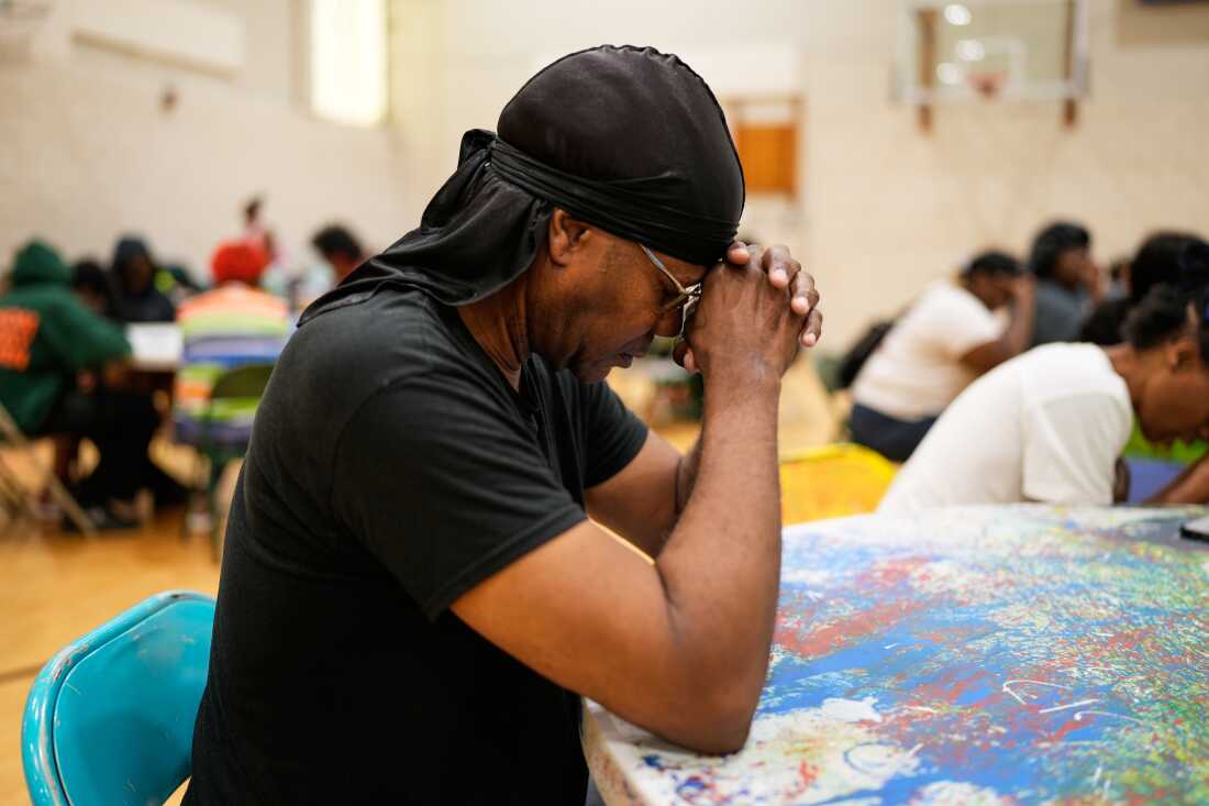 Une personne prie avant de recevoir un panier-repas gratuit au City Life Center de Gary, Indiana, le jeudi 20 août 2026, plus d'une semaine après qu'une tempête meurtrière ait traversé la région.