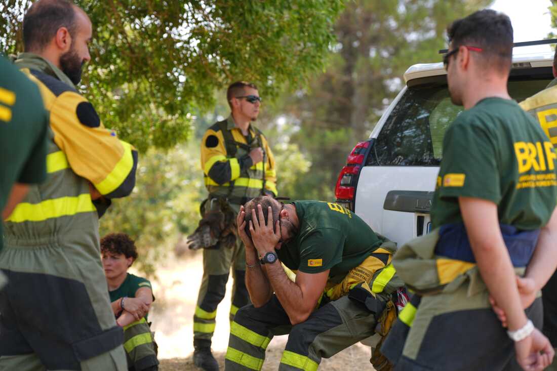 Aesir Diaz, 31 ans, technicien des Brigades espagnoles de renfort contre les incendies de forêt (BRIF), au centre, est assis à côté de ses coéquipiers pendant une pause dans la lutte contre un incendie de forêt à Sotillo de Adrada, province d'Ávila, Espagne, alors que l'incendie continue de se propager, le mardi 28 juillet 2026. 
