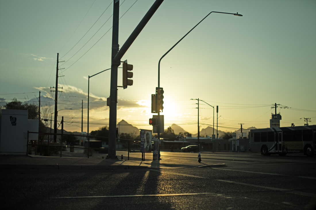 Le soleil brille derrière un lampadaire à une intersection à Tucson, en Arizona.