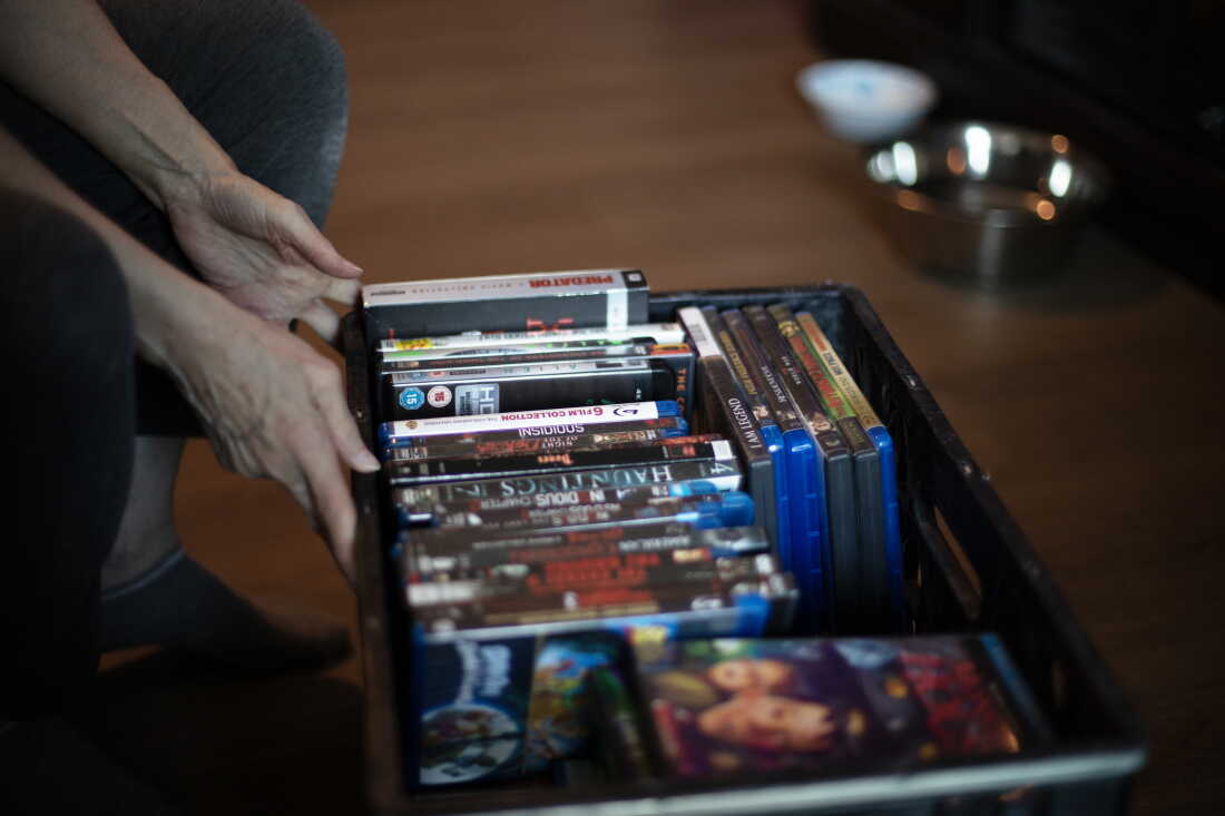 Debbie Willson sort une caisse en plastique remplie de DVD de films qu'Adam Willson avait collectés.