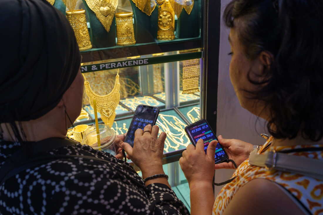 Des femmes utilisent leur téléphone pour calculer les taux de change avant d'acheter de l'or au Grand Bazar d'Istanbul, en Turquie, le 20 août 2026.