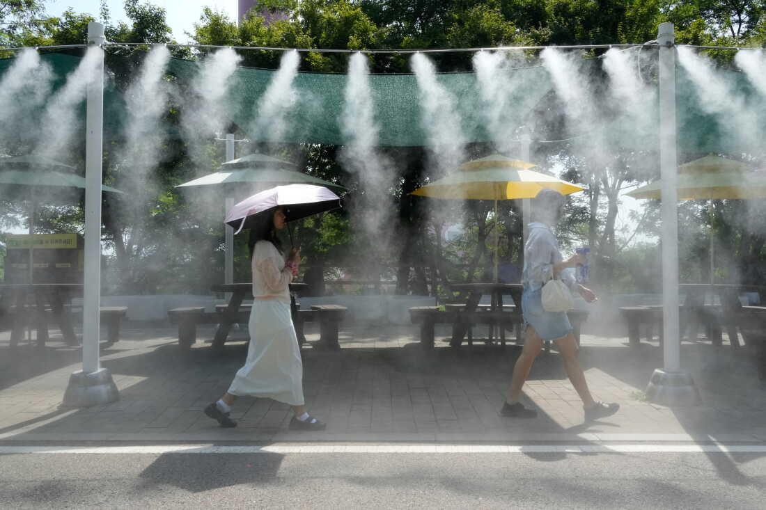 Des visiteurs passent devant le dispositif de refroidissement du brouillard sur le site touristique de la grotte de Gwangmyeong, en Corée du Sud, le 6 août 2026.