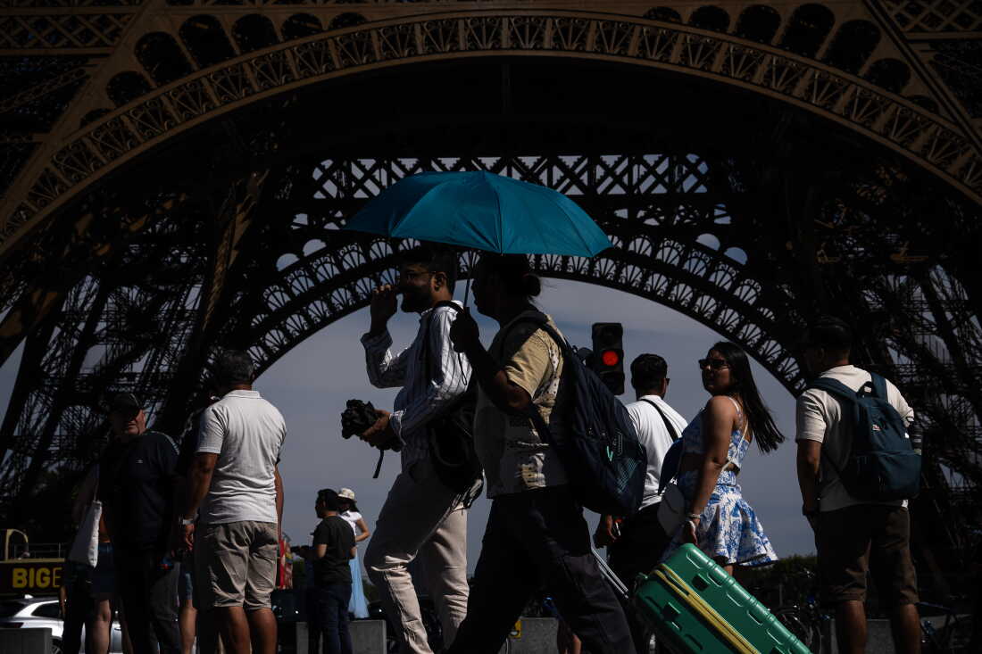 DOSSIER – Des gens marchent avec un parapluie près de la Tour Eiffel à Paris lors d’une canicule le 11 juillet 2026.