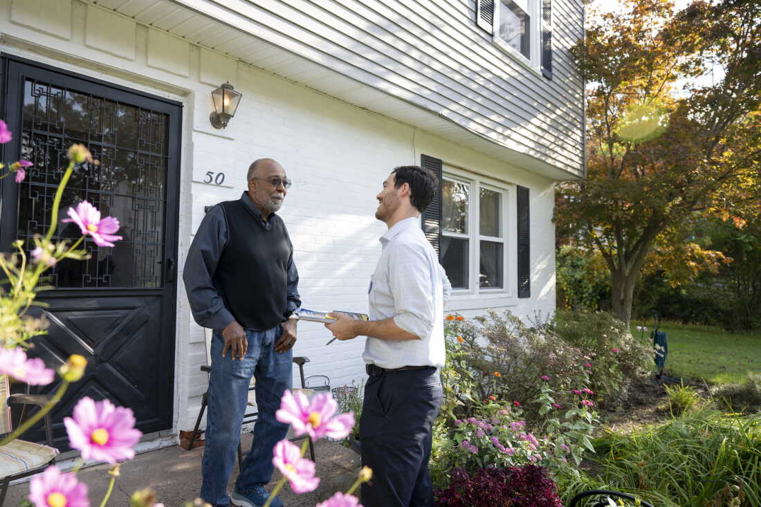 Debout devant la porte d'entrée d'une maison, James Fripp Jr. (à gauche), un habitant de New Haven, s'entretient avec Eli Sabin.