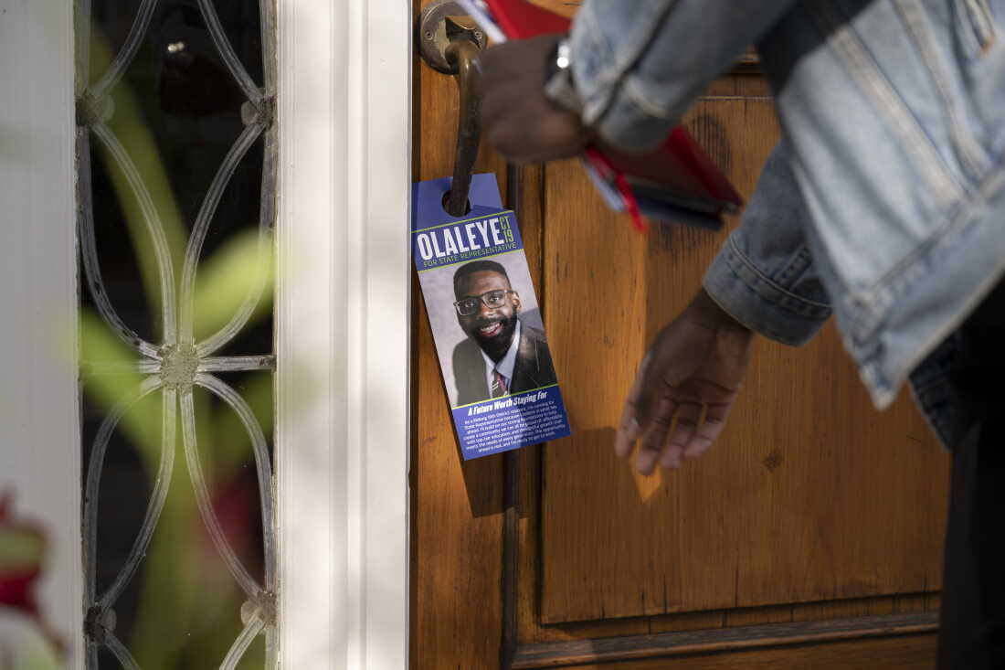 Olaleye Onikuyide laisse un dépliant de campagne sur la poignée de porte du domicile d'un électeur à West Hartford.
