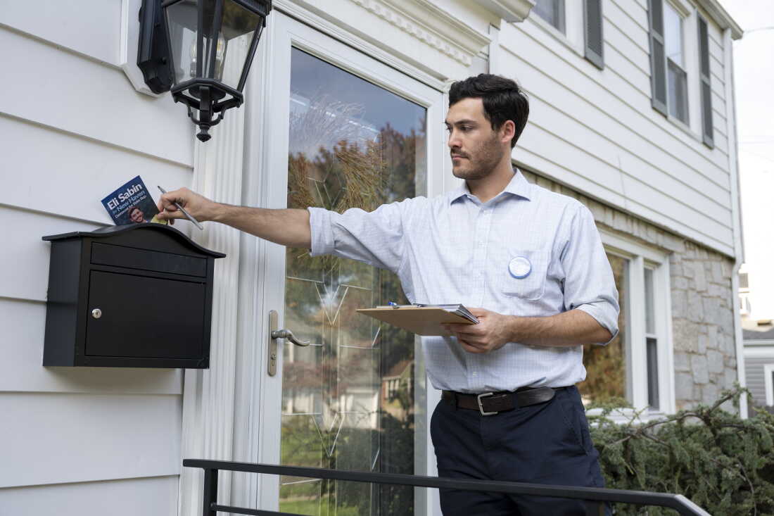 Le démocrate Eli Sabin, 26 ans, candidat au poste de représentant de l'État du Connecticut, place un dépliant de campagne dans la boîte aux lettres d'un électeur.