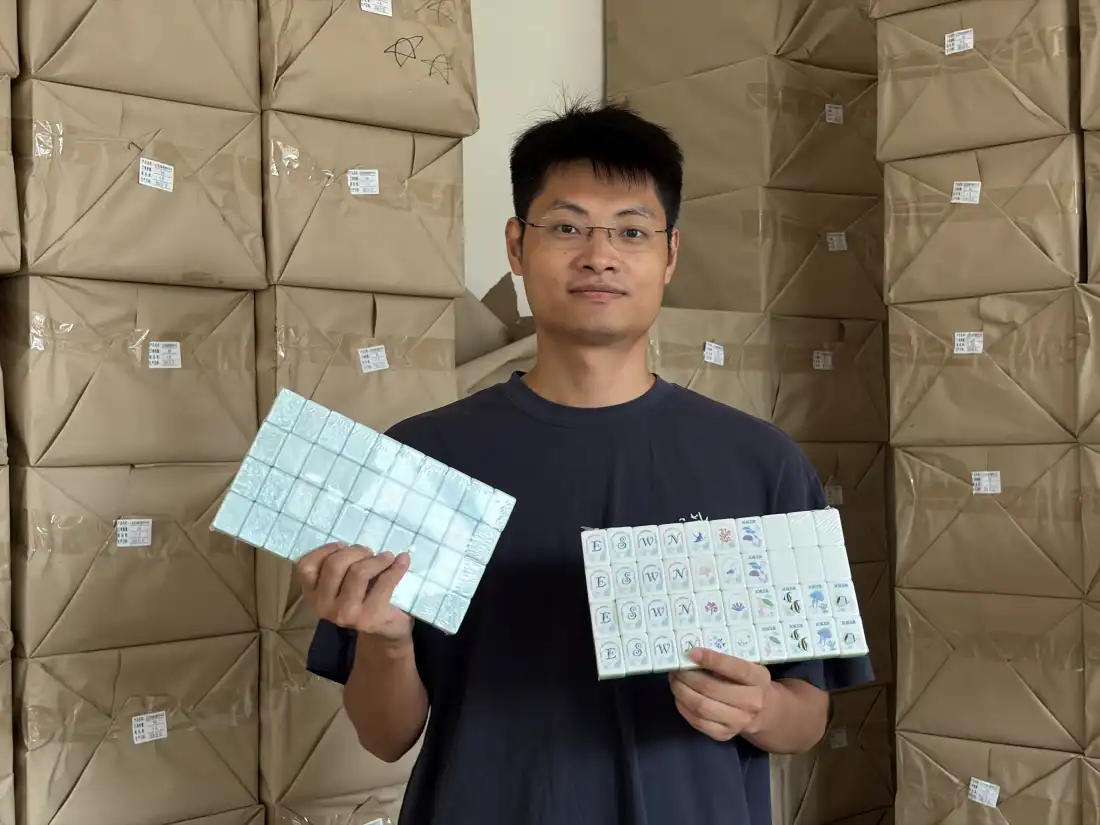 Wang Hao, copropriétaire de l'atelier de mahjong, présente un ensemble de modèles de sa marque de mahjong, Senjoy's, qui seront vendus sur le marché américain. Il s'est étendu au-delà de la distribution et s'est tourné vers la fabrication directe parce que les producteurs de la ville de Taixing ne pouvaient pas répondre à la demande américaine.