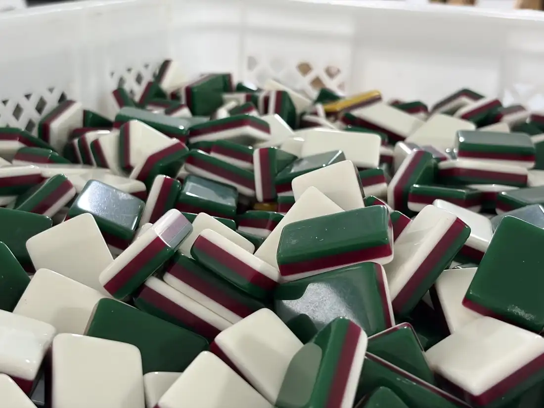 Un bac en plastique rempli de tuiles de mahjong vierges en acrylique, qui permet aux fabricants de fusionner des couches de différentes couleurs comme le blanc, le marron et le vert. Les acheteurs américains préfèrent les tuiles de mahjong plus petites et plus colorées.