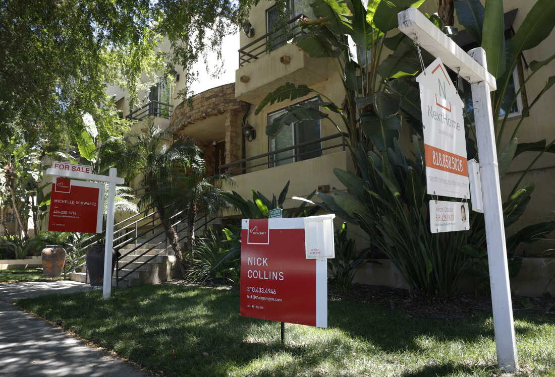 Des panneaux de vente sont plantés dans le sol devant les condominiums à vendre en juillet à Los Angeles.