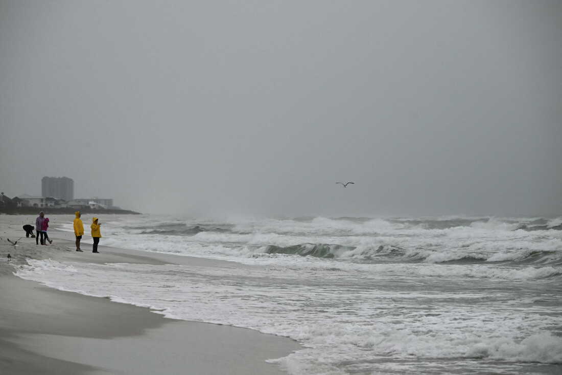 Les gens regardent les vagues se former près de la jetée du golfe de Pensacola Beach à Pensacola Beach, en Floride, le 9 octobre 2026, alors que l'ouragan Isaias continue de se déplacer vers le nord en direction de l'enclave de Floride. L'ouragan Isaias s'est intensifié jeudi en catégorie 2 dans les eaux chaudes du golfe du Mexique alors qu'il se dirigeait vers le sud des États-Unis, a annoncé le Centre national des ouragans (NHC). Premier ouragan de la saison atlantique, Isaias devrait toucher terre en Floride, en Alabama ou au Mississippi dans la nuit de vendredi à samedi, selon le NHC. (Photo de RONALDO SCHEMIDT / AFP via Getty Images)