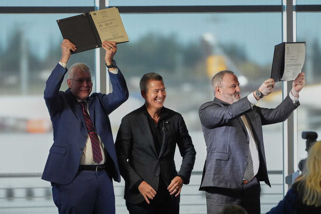 Le secrétaire américain aux Transports, Sean Duffy, au centre, réagit en présentant la certification de l'avion 737 Max 10 de Boeing à Jim Williams, ingénieur en chef du programme de développement du Boeing 737, à gauche, et à Chris Payne, vice-président et directeur de programme de Boeing Commercial Airplanes, programmes de développement du 737, à droite, le mardi 20 octobre 2026, à l'usine Boeing d'Everett, Washington.