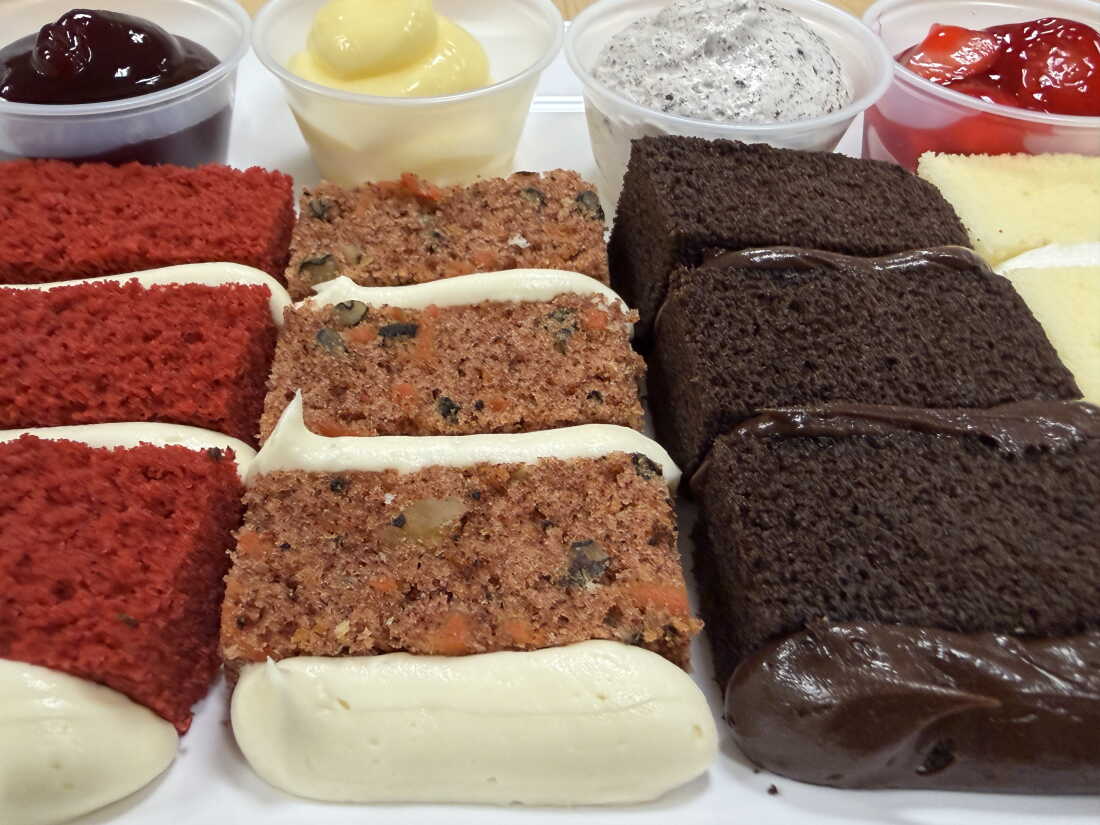 Au premier plan, une rangée d'échantillons de gâteaux de mariage dans un supermarché Publix à Vestavia Hills, en Alabama, le 23 septembre. Les saveurs du gâteau de gauche à droite sont le velours rouge, le gâteau aux carottes, le chocolat et la vanille. À l’arrière-plan se trouve une rangée de quatre petits gobelets en plastique contenant chacun un remplissage. Les saveurs de remplissage de gauche à droite sont la framboise, la crème anglaise à la vanille, la mousse aux biscuits et à la crème et la fraise.