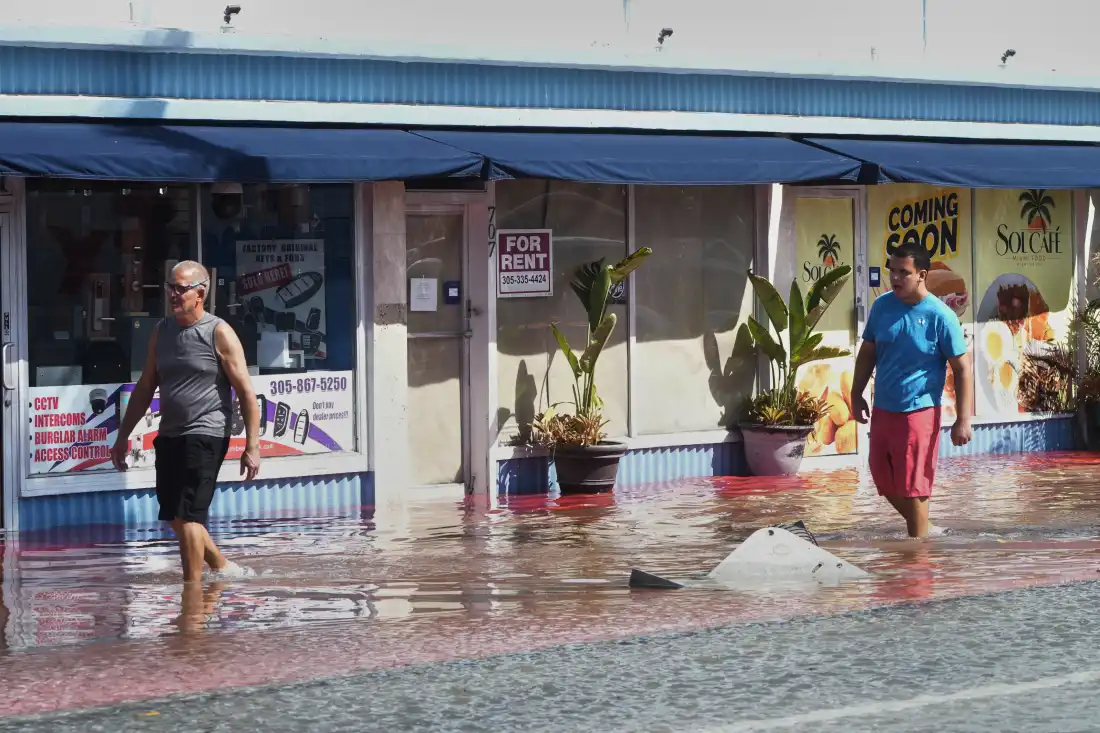 Des piétons traversent une rue inondée causée par les grandes marées et les fortes pluies le mercredi 28 octobre 2026, à North Bay Village, en Floride.