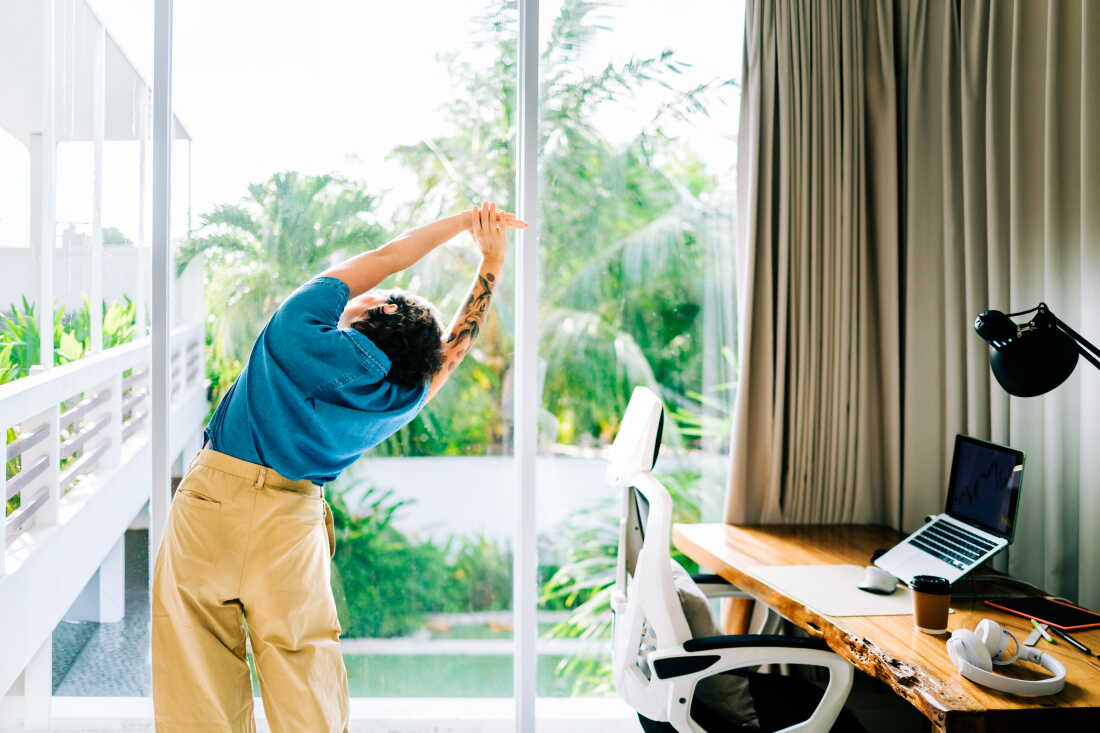 Femme démontrant un étirement latéral pendant une pause de travail au bureau à domicile.